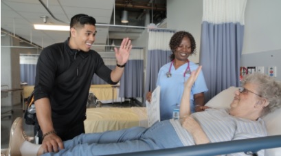 A DBCS staff member greets a client while she is in the hospital. A doctor stands by.