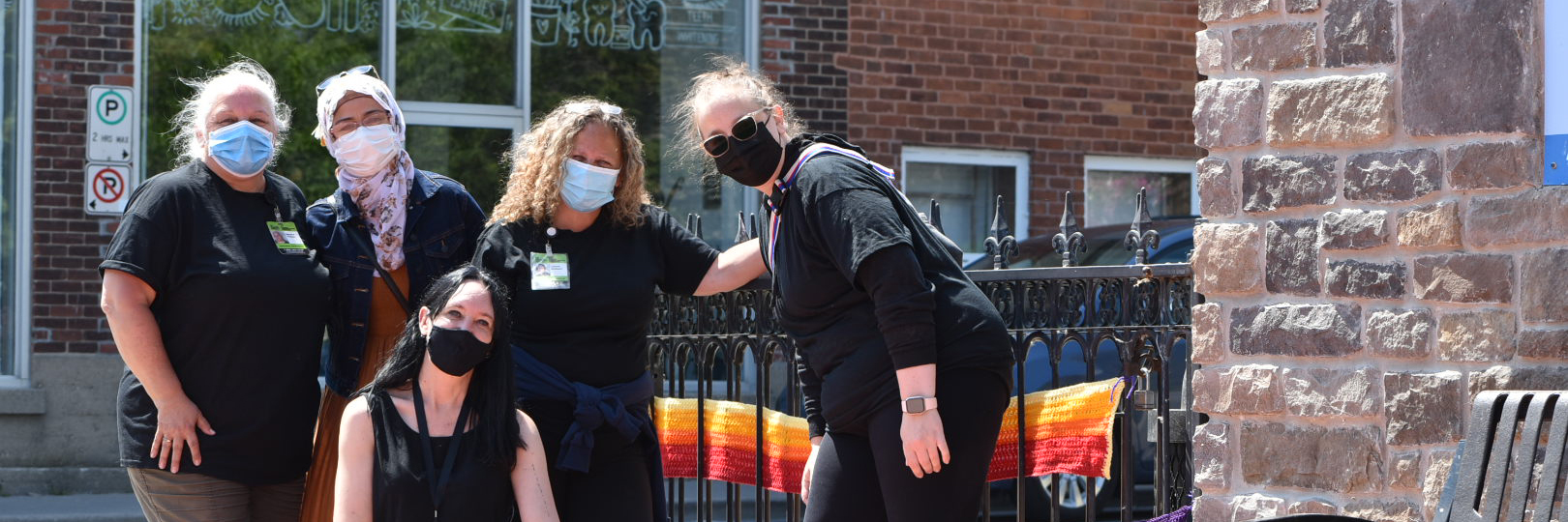 A group of DBCS staff stand together outside on a sunny day.