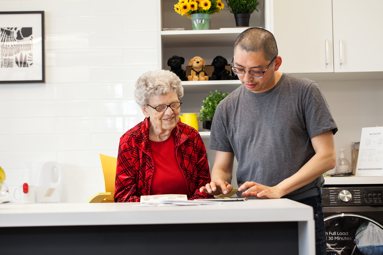 A DBCS intervenor and client sit at a kitchen and use a tablet to communicate.