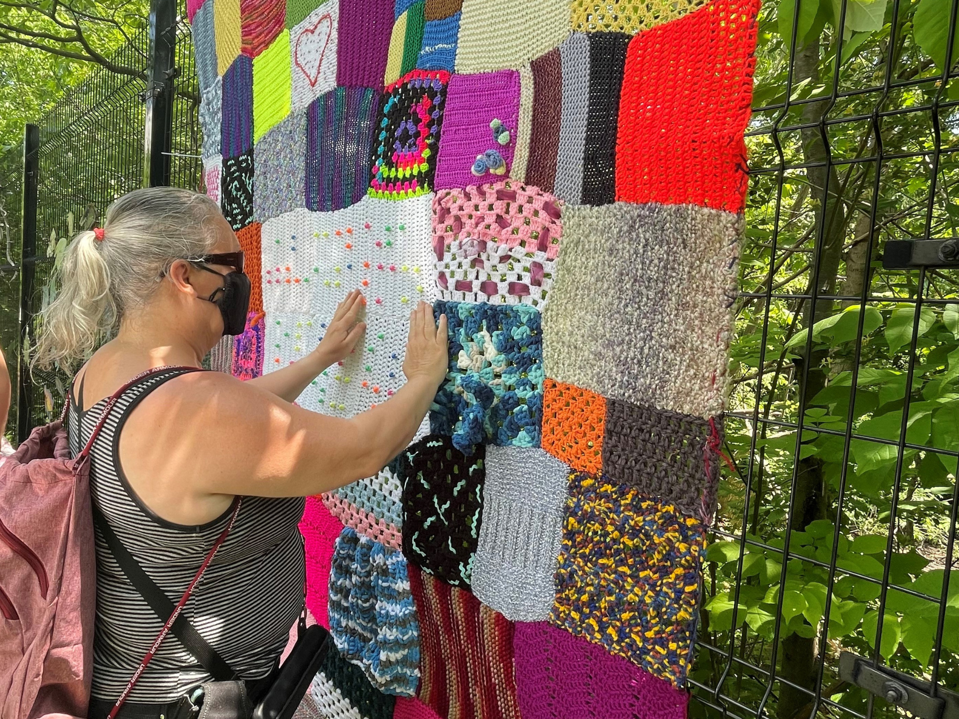 A client uses her hands to feel the tactile yarn bombing display in Missisauga