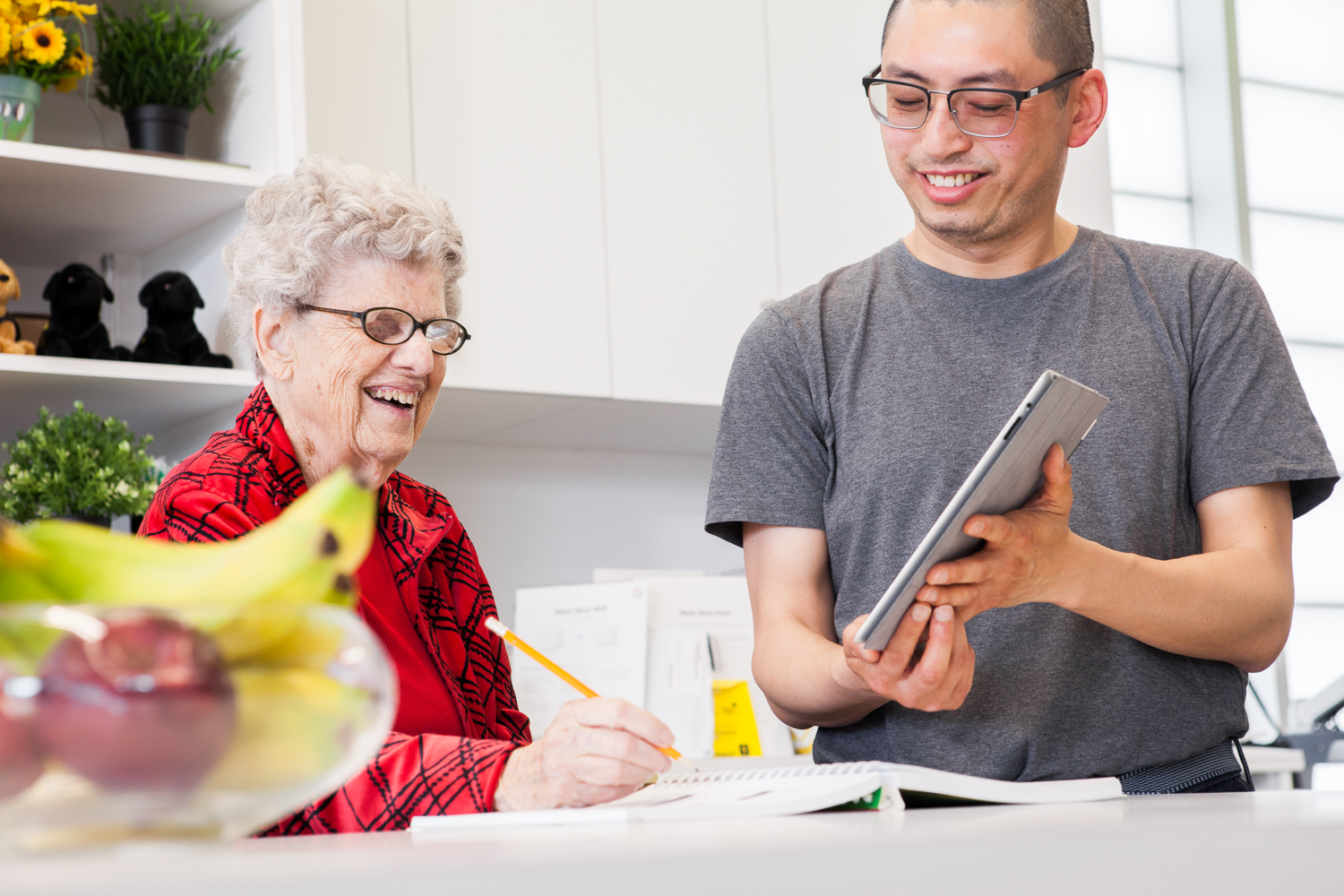 An intervenor holds a tablet up with large print notes to communicate with an older client.
