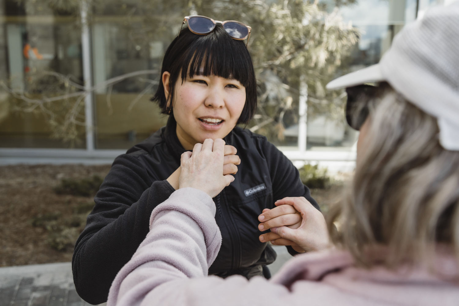 An intervenor holds a clients hands to perform tactile ASL. 