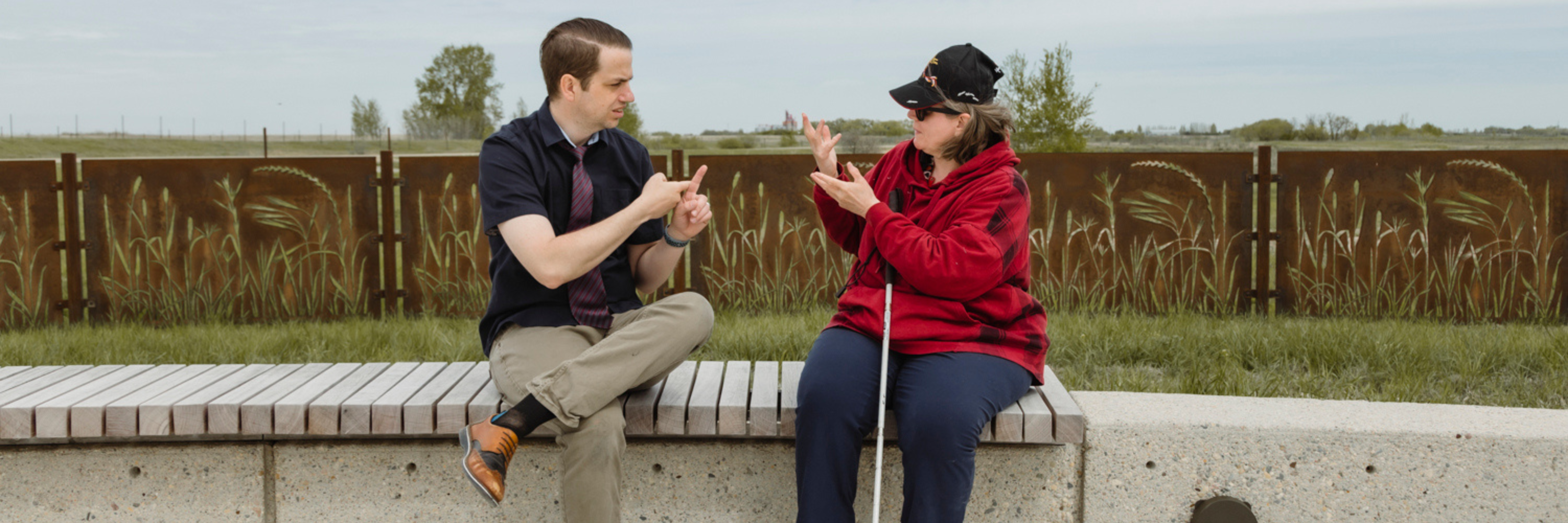 A man and woman have a conversation outside using ASL.