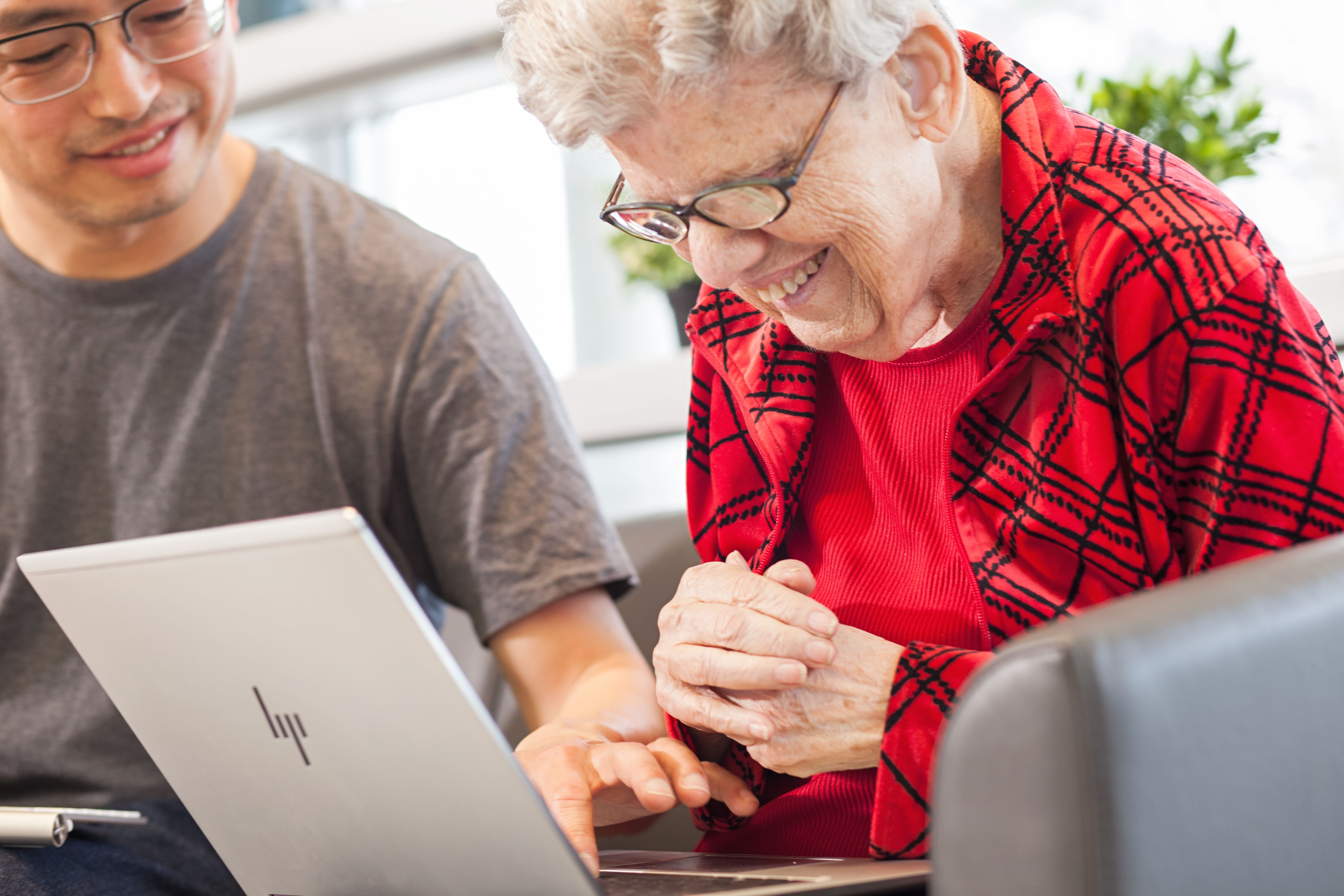 A client uses a computer to read large print notes. An intervenor points to something on the computer.