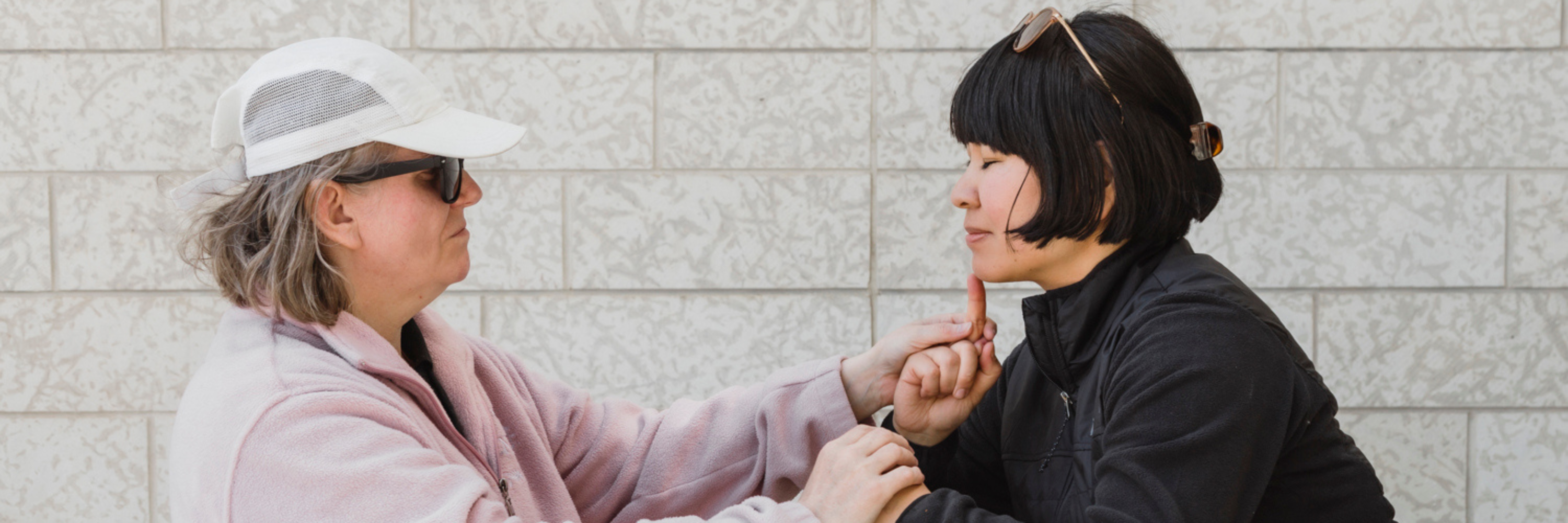 An intervenor uses tactile sign language to communicate with a Deafblind client.