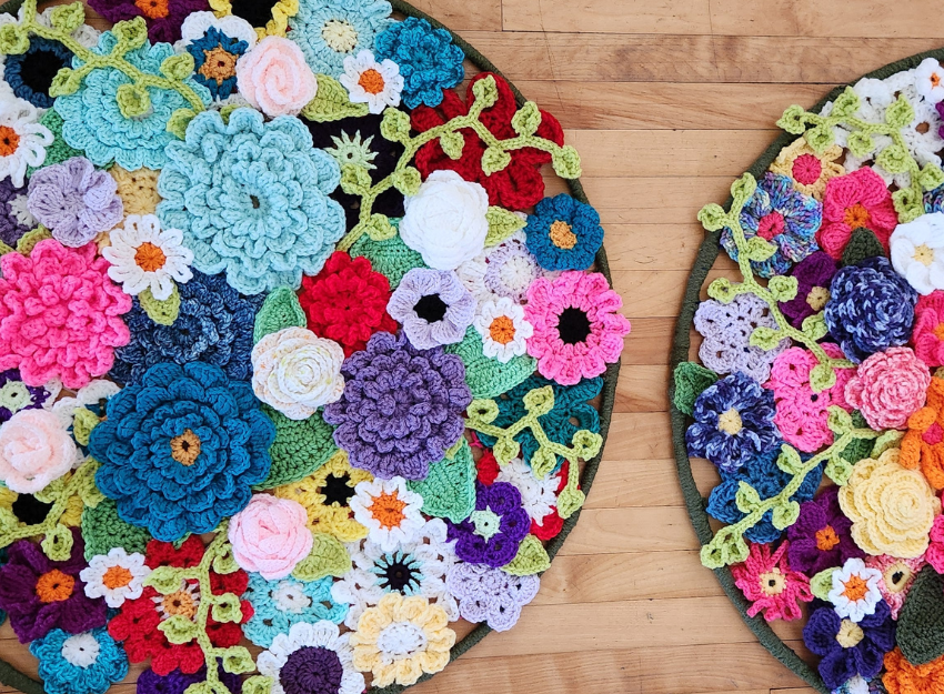 Two hoops covered in colourful crocheted flowers on the ground.