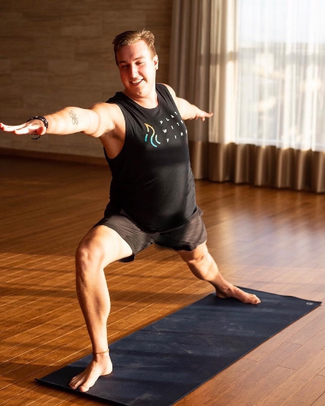A photo of Blair standing on a yoga mat doing a pose. 