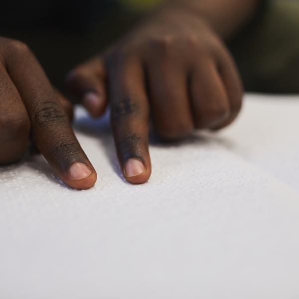 Hands trace over a braille book.