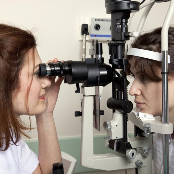 A health care professional uses equipment to examine a person's eyes.