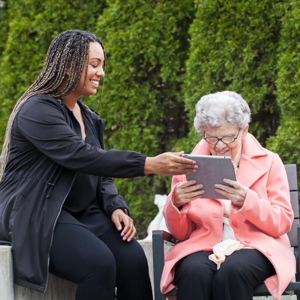 An intervenor hands a tablet to a client with a large print message written on it for them to read.